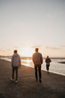 © Westend61 - Namibia, Walvis Bay, back view of three friends walking on the beach at sunset