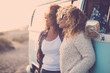 © simona - Couple of caucasian happy traveler women enjoy the trip with old vintage van feeling the sunset and the nature around her - wanderlust and alternative vacation lifestyle concept - same sex