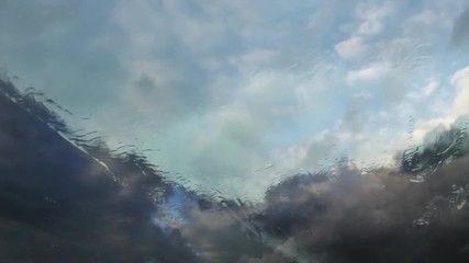 Wall Mural - rainy weather travel with dramatic storm clouds passing in front of the wet windshield of a car trav