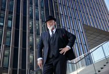 Elegant Businessman With Bowler Hat And Walking Cane, Standing On Stairs In The City
