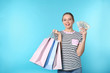 © New Africa - Portrait of happy young woman with money and shopping bags on color background. Space for text