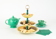 Three Tier  Mid-Century Modern Serving Dish With Yellow Glazed Plates  And Green Bakelite Stem With Brass Ring Handle For Desserts Or Appetizers With Tea Pot And Cup, Cookies And Napkins