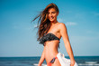 © Westend61 - Portrait of smiling young woman wearing bikini on the beach