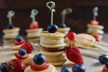 Fruit, Berry And Pancake Canapes On Wooden Table