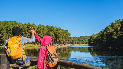  Couples travelers with backpack happy to relax on a holiday, travelers Pang-Ung park travel,Travel to visit nature landscape the beautiful at lake, at Mae-hong-son, in Thailand.