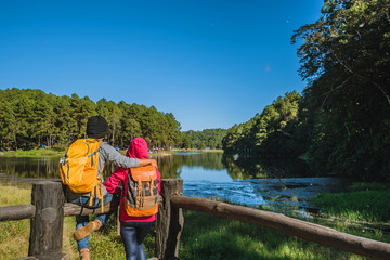  Couples travelers with backpack happy to relax on a holiday, travelers Pang-Ung park travel,Travel to visit nature landscape the beautiful at lake, at Mae-hong-son, in Thailand.