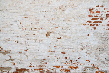 The texture of the old brick wall painted white with peeling paint