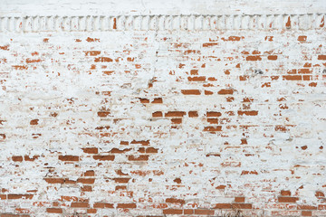 The texture of the old brick wall painted white with peeling paint