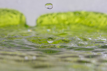 Drop of water in green background.