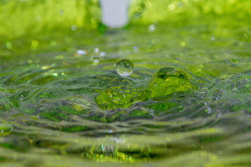 Drop of water in green background.