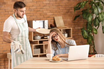 Poster - Tired wife working while her indignant husband doing chores at home