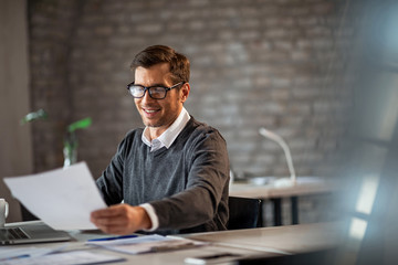 Happy businessman working on paperwork in the office.