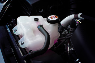 Coolant tank with a pink liquid antifreeze of a radiator system in car, automotive part concept.