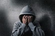 hopeless drug addict going through addiction crisis, portrait of young adult man is covering his face as wearing hood after abusing medicine and drug