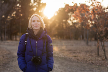 A middle-aged woman in a warm jacket is smiling on nature.