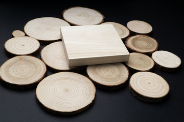 Wall Mural - Pine tree cross-sections with annual rings and wooden square onblack surface. Lumber piece close-up shot, top view.