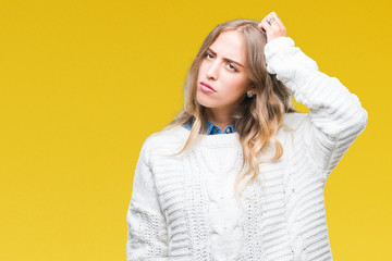 Poster - Beautiful young blonde woman wearing winter sweater over isolated background confuse and wonder about question. Uncertain with doubt, thinking with hand on head. Pensive concept.