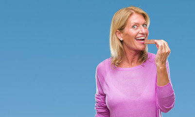 Poster - Middle age blonde woman eating chocolate bar over isolated background with a confident expression on smart face thinking serious