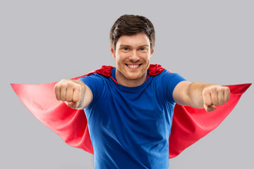 Wall Mural - super power and people concept - happy young man in red superhero cape over grey background