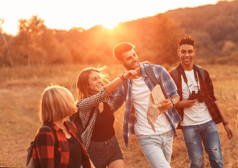 Wall Mural - Group of four friends hiking through countryside together at sunset.