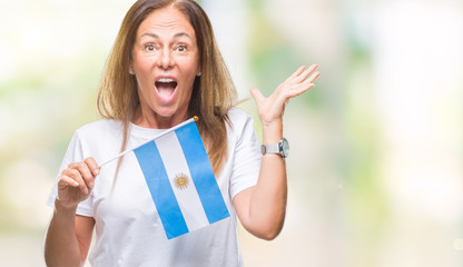 Middle age hispanic woman holding flag of Argentina over isolated background very happy and excited, winner expression celebrating victory screaming with big smile and raised hands