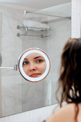 Wall Mural - Skin care. Woman touching hair and smiling while looking in the mirror.Portrait of happy girl with wet hair in bathroom