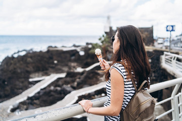 Wall Mural - Pretty brunette girl eating ice cream and walking outdoor on the street.