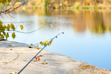 Fishing rod, spinning reel on the background pier river bank