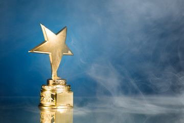 gold star trophy in smoke, blue background