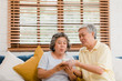 © tirachard - Asian elderly couple man holding cake celebrating wife's birthday in living room at home. Japanese couple enjoy love moment together at home. Lifestyle senior family at home concept.