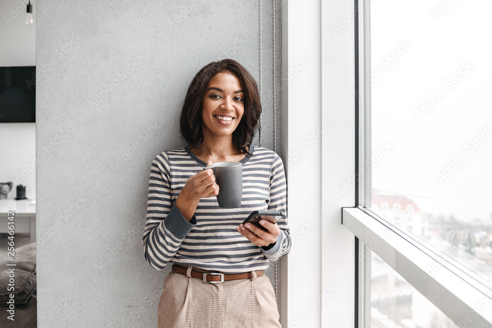 Smiling african woman using mobile phone Stock Photo | Adobe Stock