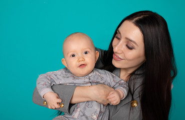 Young mother holding her newborn child. Woman and new born boy relax on color background. Mother breast feeding baby. Family at home. Young mother playing with her newborn son