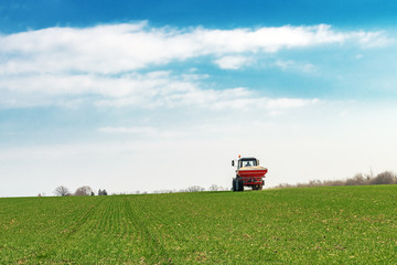 Wall Mural - Agricultural tractor fertilizing wheat crop field with NPK