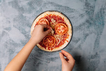 Cooking Italian Pizza With Tomatoes, Chicken, Olives On Wooden Background. Tomato Sauce On The Dough By Woman's Hand .