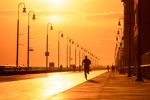 Silhouette Of A Person Running On A Boardwalk At Sunset. People Enjoying Outdoor Activities Under Golden Light - Long Beach New York