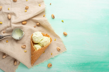 Wall Mural - pistachio ice cream cones with pistachios and a spoon for ice cream. On a mint background.Flat lay