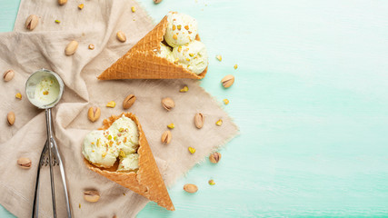 Wall Mural - pistachio ice cream cones with pistachios and a spoon for ice cream. On a mint background.Flat lay