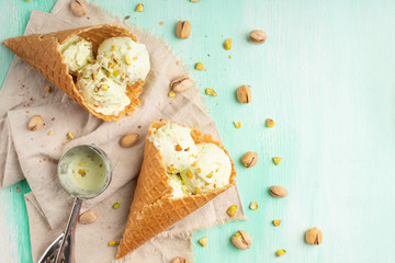 Wall Mural - Pistachio ice cream with pistachio nuts and a spoon for ice cream on a light mint background. Top view, Flat lay. Summer mood