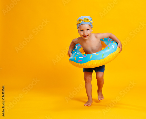 Fotomural happy child boy in swimsuit with swimming ring donut on colored yellow background