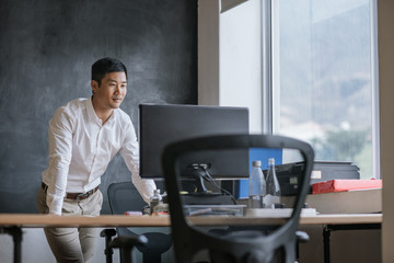 Smiling Asian businessman working on his computer in an office