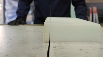 Wall Mural - Close up of a young man in a furniture factory cutting the foam for the sofa