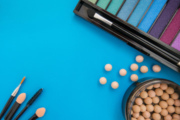 Top, up view of professional cosmetics, makeup background. Brushes, eye shadows, eyebrow pencils, powder, bronzing balls, mascara, red lipstick. Tools isolated on blue. Concept of get ready for party