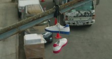 Generic White Sneakers Hanging From Street Light Pole On Gritty Urban Street, Seen High Angle From Above.