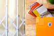 Modern lockable yellow postbox with many mail letter inside. Brick wall and steel doors background.