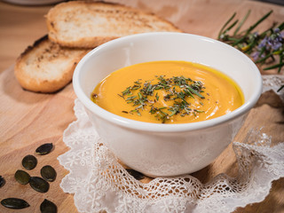 smooth creamy pumpkin soup in a bowl on wood background. healthy vegetable mashed with thyme on surface 2