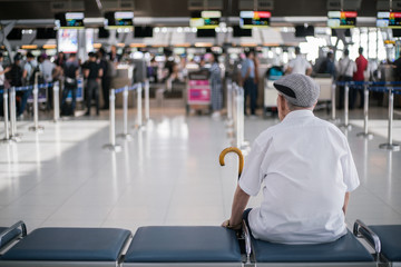 Elder man sitting in front of the check in counter waiting for his family