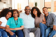 Grandparents with teen and young adult grandchildren sitting at home smiling to camera