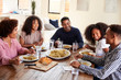 © Monkey Business - Middle aged black couple sitting at dinner table eating with their children, close up
