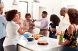 © Monkey Business - Middle aged black man pouring champagne to celebrate at home with his three generation family