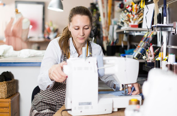 Portrait of woman designer who is working with sewing machine